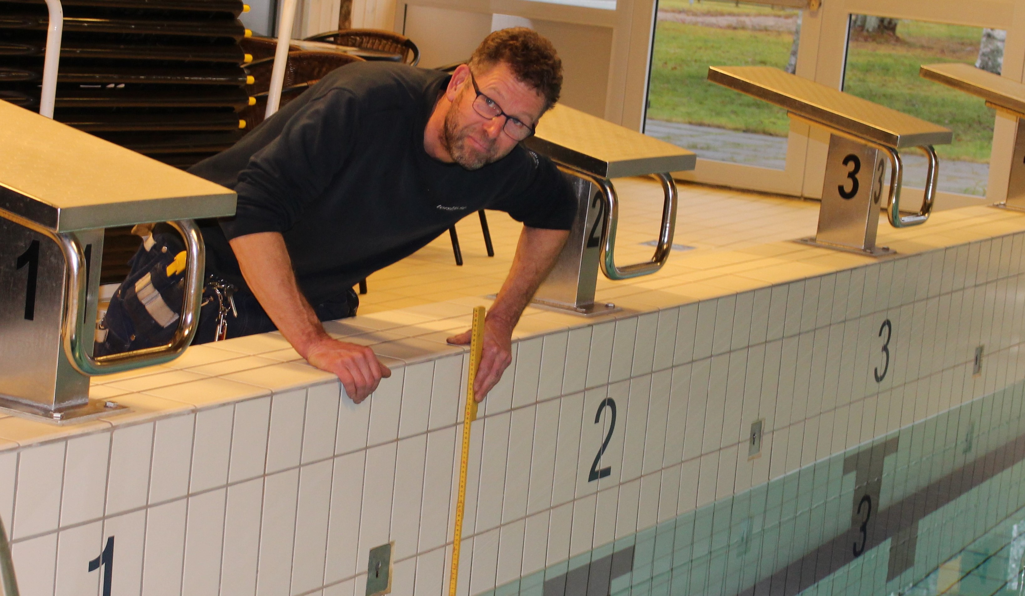 Vaktmästaren mäter vattennivån i bassängen